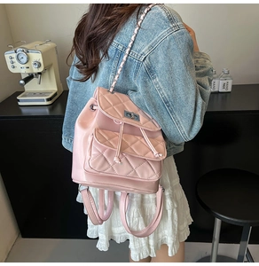 Detailed view of pink quilted leather backpack with chain strap on a model