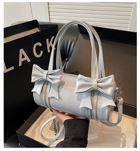 Close-up of light blue bow handbag with silver hardware and detachable strap detail