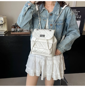 Close-up of white quilted PU leather backpack with silver chain strap on a model