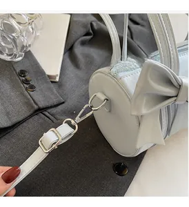 Detailed shot of a blue cylinder handbag with a large bow on a grey blazer