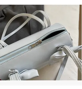 Close-up of smooth silver zipper and leather texture on light blue cylinder bag