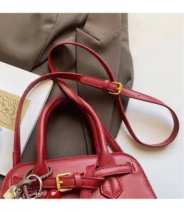 Detail of red faux leather tote bag with lychee texture and heart cherry charms