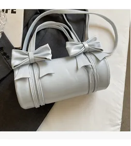 Close-up of light blue cylindrical handbag with dual bow accents and textured synthetic leather