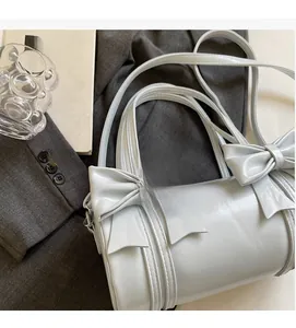 Close-up of light blue cylindrical handbag with bow details and glossy PU leather finish