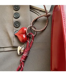 Detail of red heart keychain with striped cord and beads on a leather tote bag