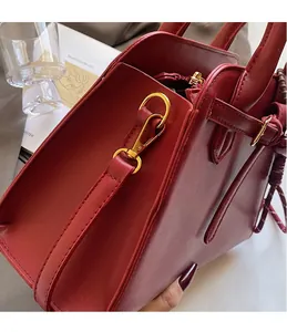 Detailed close-up of premium red tote bag with high-quality gold metal hooks and buckle
