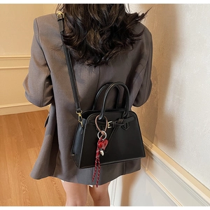 Detailed view of the black tote bag with a red heart pendant and braided cord accent