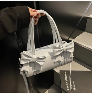 Close-up of light blue cylindrical barrel bag with glossy finish and large bow details