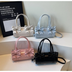 Row of four colorful cylinder handbags featuring decorative bows and shiny leather finish