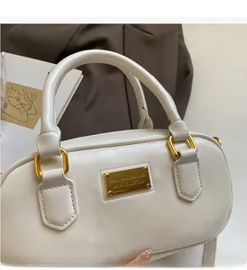 Detailansicht der elfenbeinfarbenen Ledertasche mit elegantem goldenem Metall-Logo