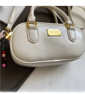 Detailansicht der cremefarbenen Bowlingtasche aus Leder mit goldener Plakette und Perlen