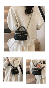 Close-up of black quilted leather mini box bag with gold flower buckle and chain strap