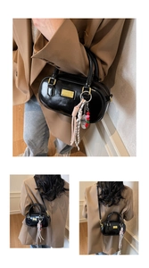 Detailansicht der schwarzen glänzenden Boston-Tasche mit goldener Metallplakette