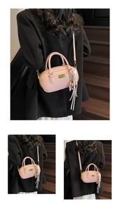 Detailaufnahme einer rosa Boston-Tasche mit goldenen Beschlägen und modischem Anhänger