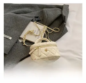 Close-up of quilted cream mini bag with gold flower hardware on a textured grey coat