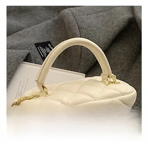 Detailed close-up of cream quilted leather box bag with gold chain and curved handle