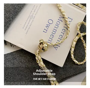 Macro detail of gold-tone ball adjustment buckle on white leather chain strap