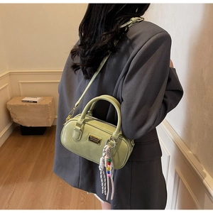 Détail du sac Boston vert clair avec plaque dorée et breloque perlée décorative