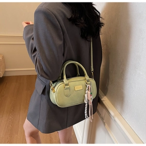 Détail du mini sac Boston vert clair avec bandoulière et pendentif foulard rayé