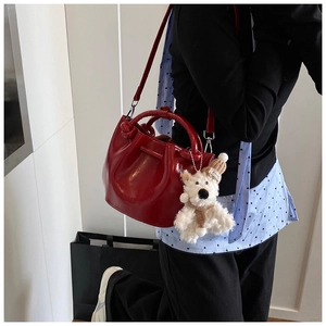 Red glossy bucket bag for women, trendy chic handbag with cute bear pendant for daily outfits.