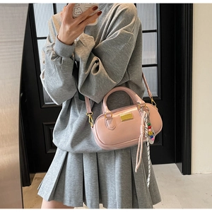 Rosa Boston-Handtasche mit goldener Hardware und buntem Perlenanhänger im Detail