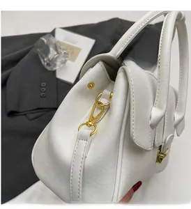 Detailed close-up of white leather handbag featuring premium gold metal hardware and hooks