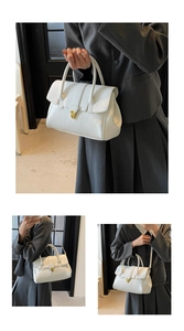 Detailansicht einer weißen minimalistischen Handtasche mit goldenem Drehverschluss