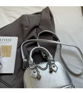 Borsa a conchiglia argento con catena a dadi e tracolla su un blazer grigio