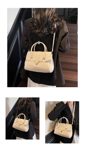 Detail der beigen Kunstledertasche mit goldenem Dreiecksverschluss und Tragegriff