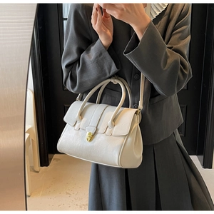 Detail of cream leather handbag with gold twist lock and adjustable shoulder strap