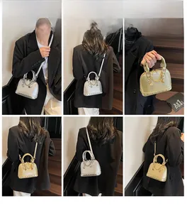 Dettaglio della borsa a conchiglia oro con borchie e accenti di catena in metallo