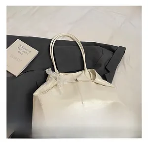 Close-up of cream PU leather tote bag with lace pearl bow detail on the shoulder strap