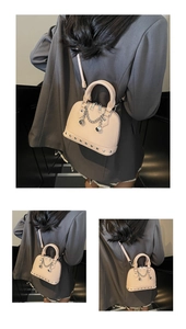 Dettaglio borsa a conchiglia beige con ciondoli a dado argentati e borchie in metallo