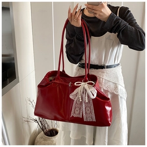 Detail of red glossy leather tote bag with white lace bow and pearl decoration