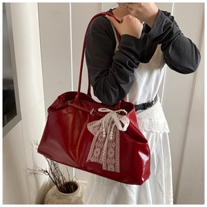 Detail of red glossy faux leather tote bag with white lace bow and pearl pendants