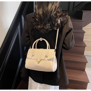 Chic cream-colored small square handbag shown on a model in a minimalist setting