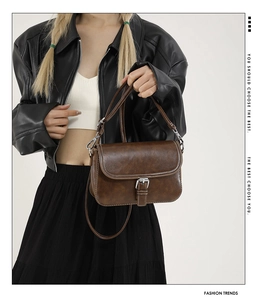 Détail du sac bandoulière marron rétro avec coutures contrastées blanches et boucle argent