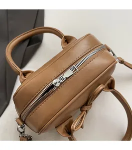 Dettaglio della cerniera argentata e del fiocco sulla borsa bowling vintage marrone