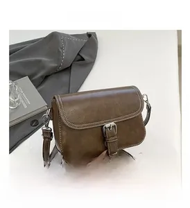 Détail du sac bandoulière vintage marron avec coutures blanches et boucle métallique