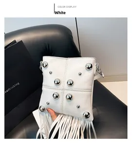 Detalle de bolso bandolera de cuero blanco con remaches plateados y borlas largas