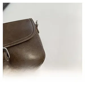 Gros plan sur le cuir synthétique marron avec surpiqûres blanches et boucle métallique