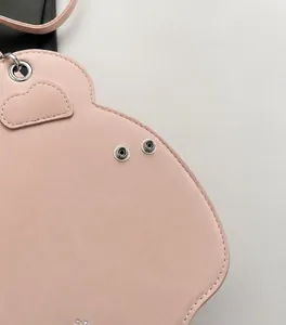 Vista macro di cuciture e toppa in pelle a cuore su uno zaino rosa da ragazza
