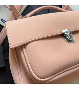 Close-up of pink leather handbag showing matte texture, silver twist lock and stitching