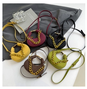 Detalle de mini bolsos de media luna en varios colores con asa de cadena dorada gruesa