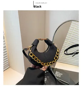 Detalle del bolso de media luna negro con cadena dorada y correa sostenido por modelo
