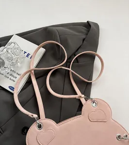 Dettaglio tracolla della borsa rosa con occhielli metallici su un blazer grigio