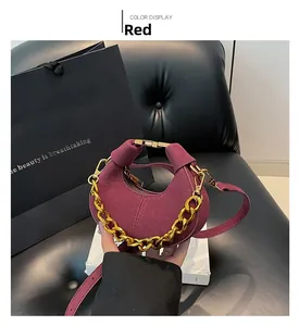 Detalle de bolso media luna de ante burdeos con cadena dorada y correa de cuero