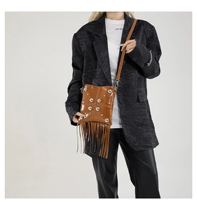 Dettaglio della borsa con frange in pelle marrone vintage con borchie su modella