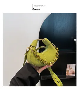 Detalle de mini bolso media luna de ante verde con cadena dorada y correa ajustable