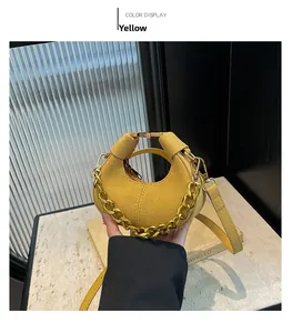 Detalle de bolso de media luna amarillo mostaza con cadena dorada y textura fina